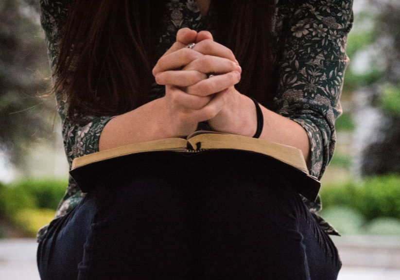 person-sitting-while-reading-book-and-praying