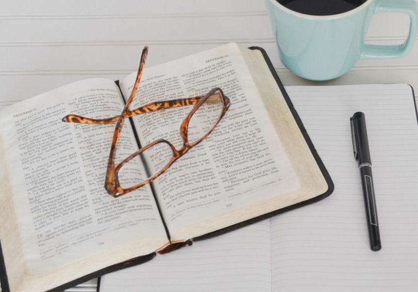 tortoiseshell-eyeglasses-on-top-of-book-near-black-pen-and-teal-mug