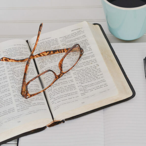 tortoiseshell-eyeglasses-on-top-of-book-near-black-pen-and-teal-mug